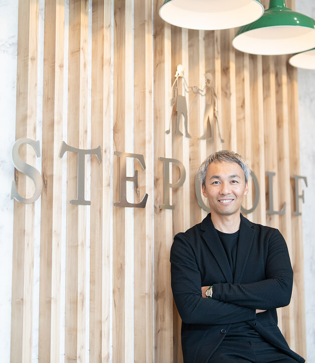 笑顔で腕を組むステップゴルフ株式会社 代表取締役 CEO 榎本 考修